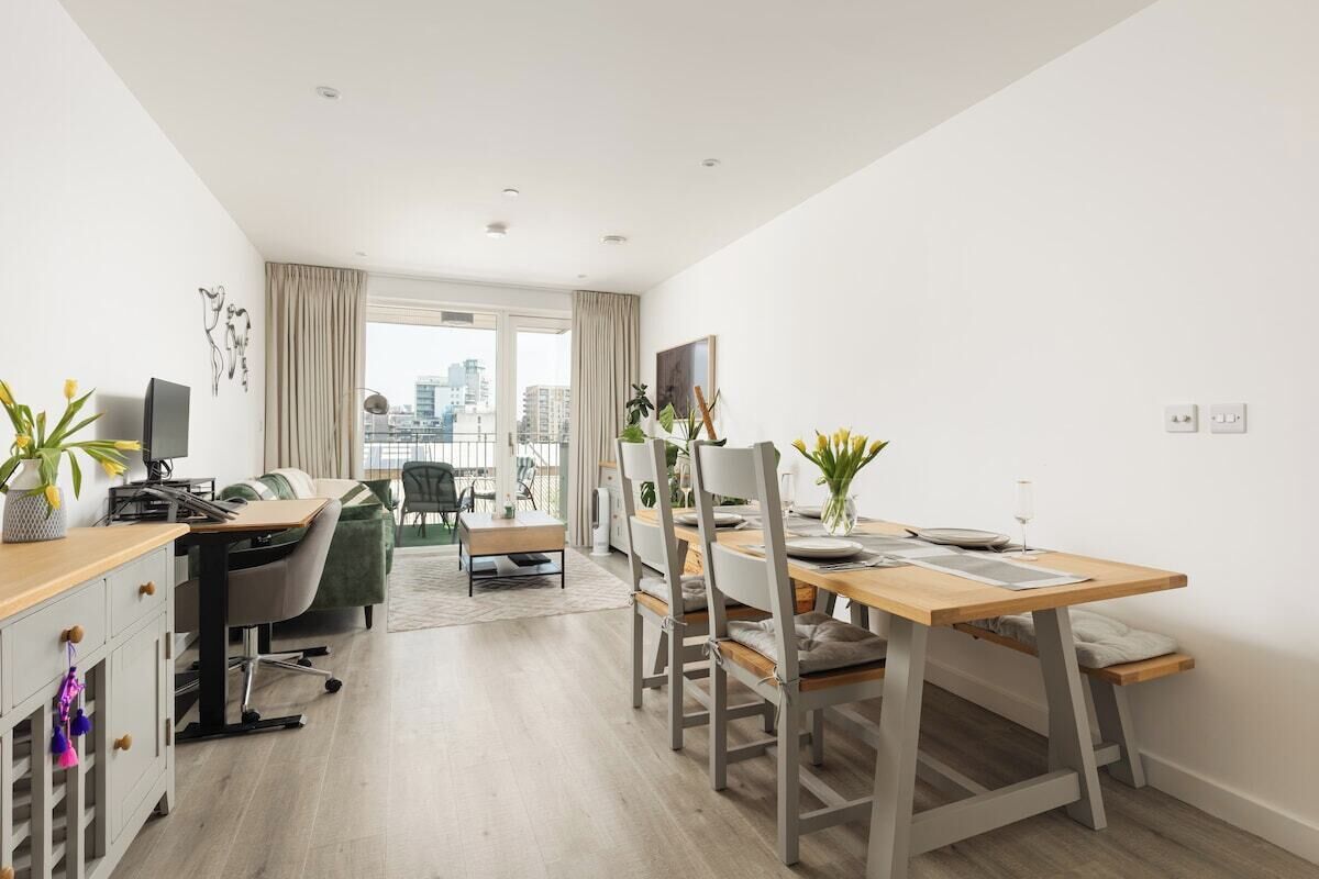 A modern apartment with a dining area, a workspace, and a view of the city.
