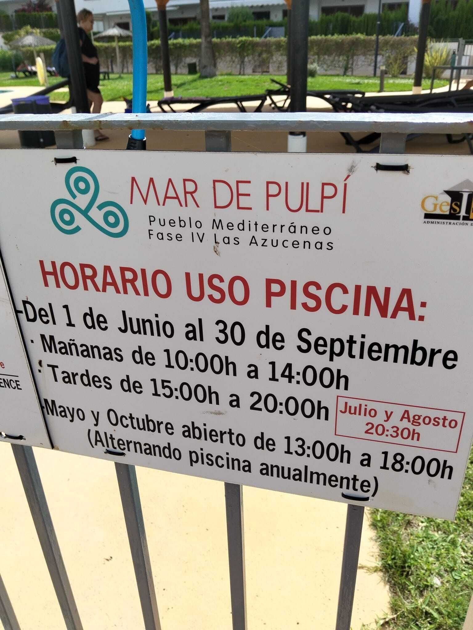 A sign with the text 'MAR DE PULPÍ Pueblo Mediterráneo Fase IV Las Azucenas' and 'HORARIO USO PISCINA' with operating hours.