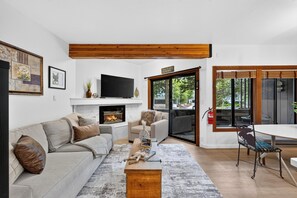 Una sala de estar moderna con chimenea, sofá, mesa de centro y comedor con mesa y sillas.