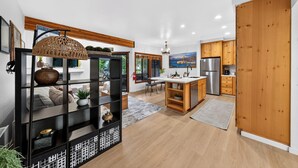 A modern kitchen with wooden cabinets, a central island, and a dining area with a view of the outdoors. - Walk to Lifts + Tram and KT-22 Views | Olympic Valley | Tram Condo (Olympic Valley)