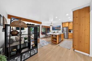 A modern kitchen with wooden cabinets, a central island, and a dining area with a view of the outdoors. - Walk to Lifts + Tram and KT-22 Views | Olympic Valley | Tram Condo (Olympic Valley)