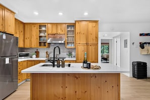 Una cocina moderna con armarios de madera, un refrigerador de acero inoxidable, un microondas y una isla grande con pileta.
