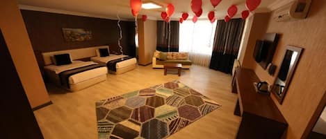 A hotel room with a sofa set, a patterned rug, and a television.