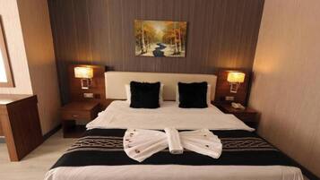 A hotel room with a bed, two bedside tables, a headboard, and a painting on the wall.