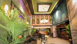 A lobby with a high ceiling, a chandelier, seating area, and potted plants. - Royal Berk Hotel (VAN)