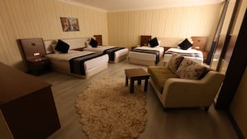 Habitación de hotel con dos camas, un sofá, una mesita y un tapete decorativo.