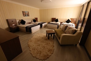 Habitación de hotel con dos camas, un sofá, una mesita y un tapete decorativo.