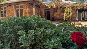 A stone building with a covered porch and a stone chimney. - Highwoods Cottage - Authentic charm in the heart of Wine Country (Pokolbin)