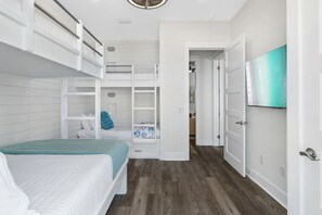 A bedroom with a bunk bed, a walk-in closet, and a TV mounted on the wall. - Wanderlust by AvantStay | Walk to Beach + Pool | New Construction (Panama City Beach)
