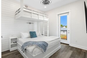 A bedroom with a bunk bed, a bedside table, a window with a view of the outside, and a ceiling fan. - Wanderlust by AvantStay | Walk to Beach + Pool | New Construction (Panama City Beach)