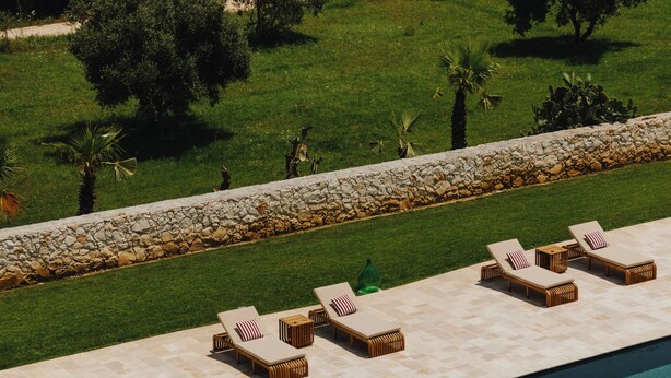 A poolside area with lounge chairs and a stone wall. - Villa Gloria (Monteroni di Lecce)