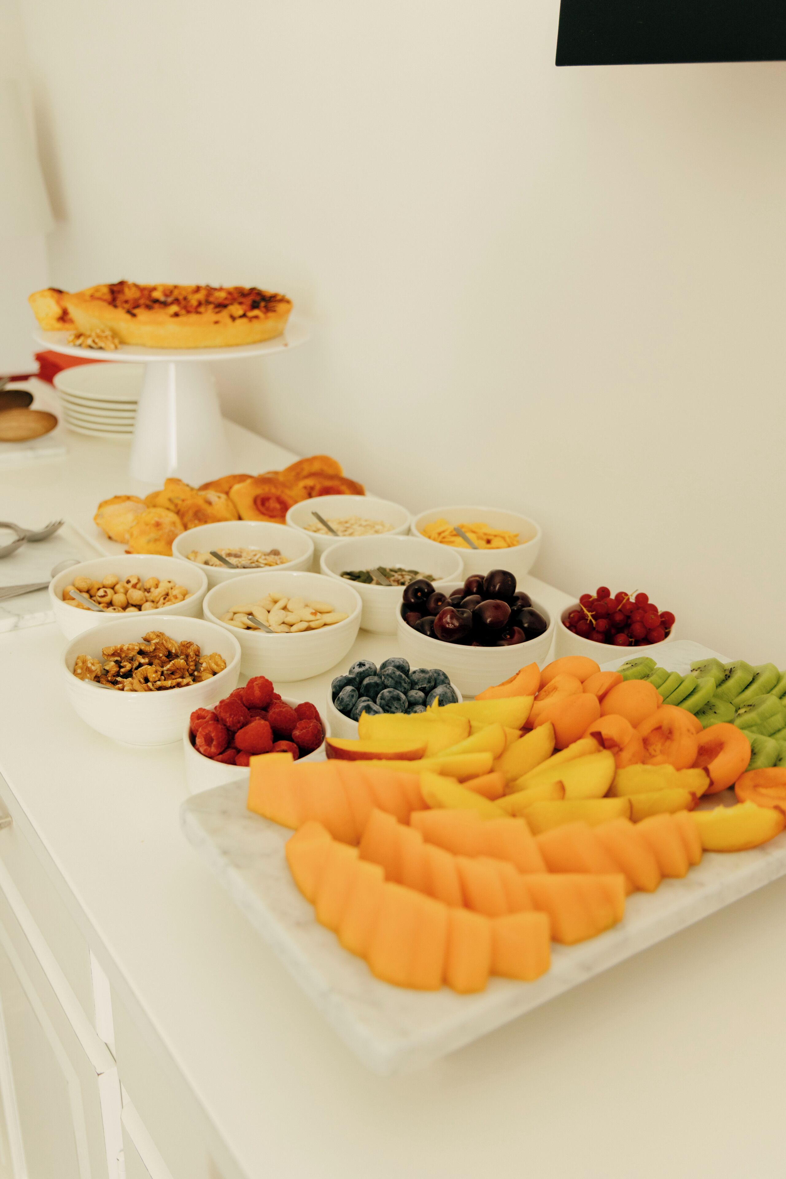 A buffet table with various food items including fruits, nuts, and pastries.