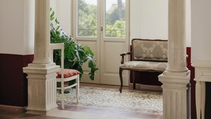 A room with a large arched doorway, a chair, a table, and a view of greenery outside. - Villa Gloria (Monteroni di Lecce)