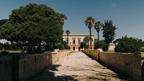 A pathway leading to a building with columns, surrounded by trees and a clear sky. - Villa Gloria (Monteroni di Lecce)