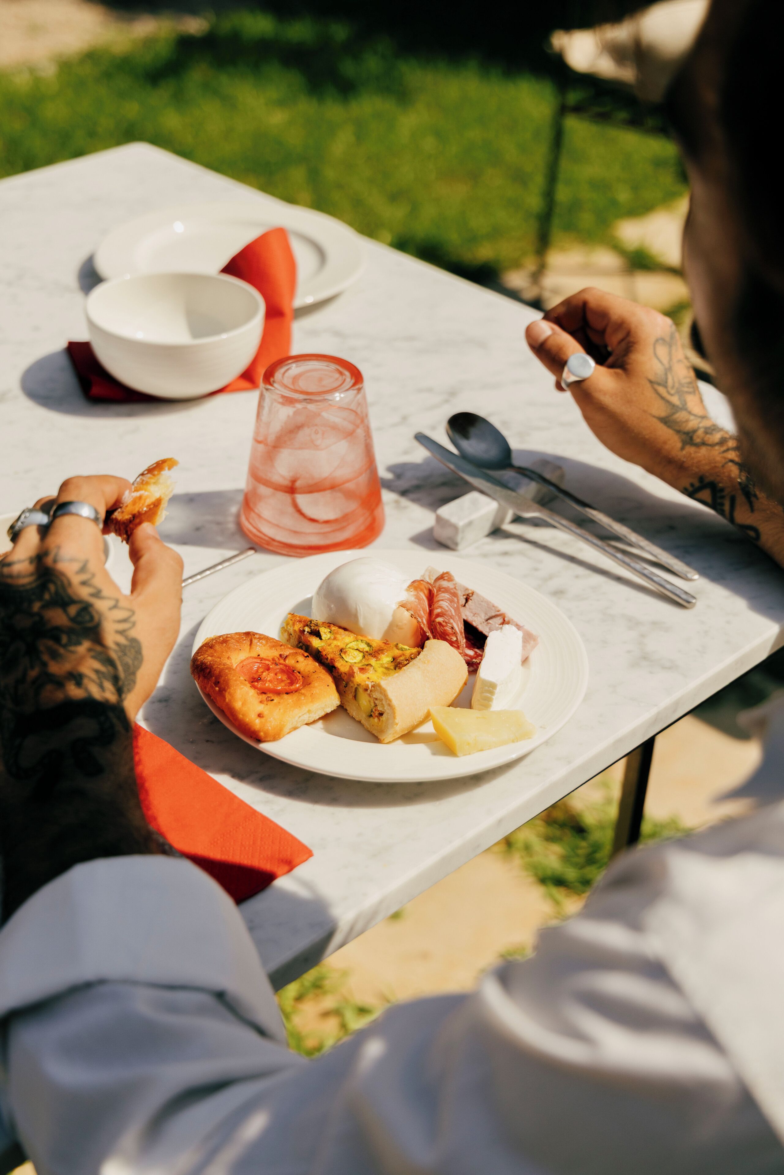 A table with a plate of food, a glass of drink, and cutlery.
