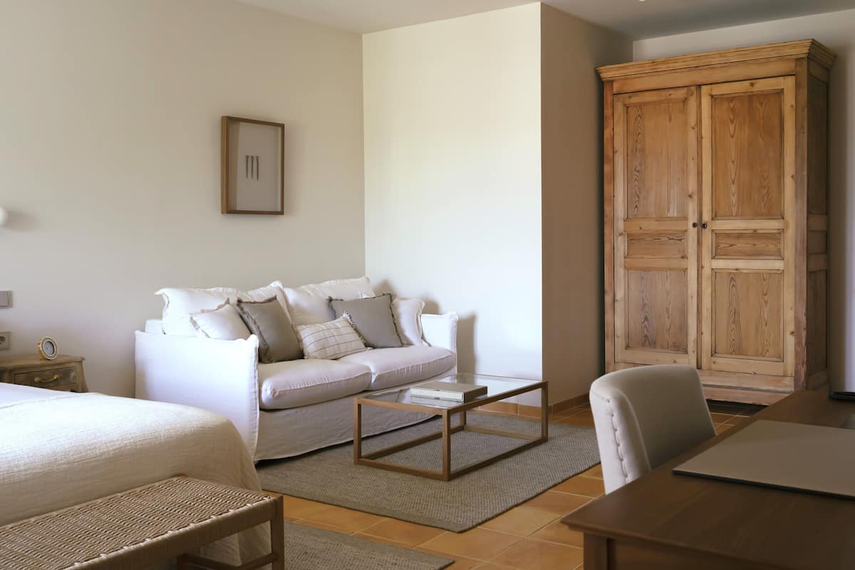 Une chambre à coucher comprenant un lit, un canapé, une armoire en bois et une table basse.