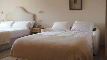 A hotel room with two beds, a bedside table with a radio, and a framed picture on the wall.