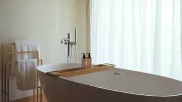 Ein modernes Badezimmer mit einer freistehenden Badewanne, einem Handtuchhalter und einem Duschkopf.