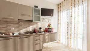 A modern kitchen with a flat-screen TV, a microwave, and a kettle on the counter. - Martina (Bologna)