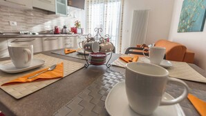 A modern kitchen with a dining area, a coffee station, and a view of the outdoors. - Martina (Bologna)