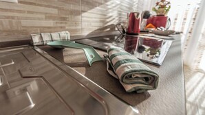 A kitchen counter with a green cutting board, a rolled towel, and a red mug. - Martina (Bologna)