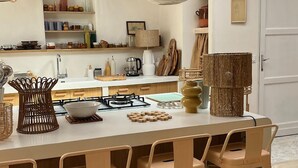 Uma cozinha com ilha central, banquetas de bar, lanternas de papel penduradas e vigas de madeira.