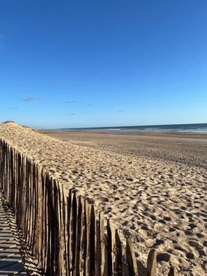 Ein Sandstrand mit einer Holzzaun im Vordergrund.