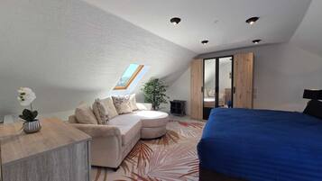 Ein Schlafzimmer mit einem Bett, einem Sofa, einem Schreibtisch und einer Pflanze.