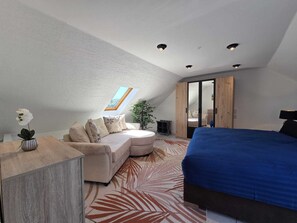 Ein Schlafzimmer mit einem Bett, einem Sofa, einem Schreibtisch und einer Pflanze.