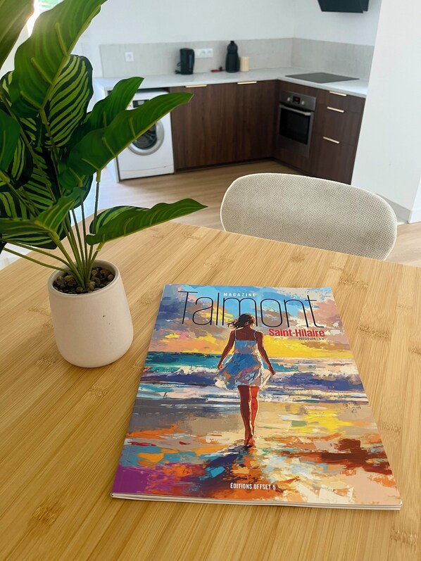 Una revista sobre una mesa de madera con una planta en maceta a su lado.