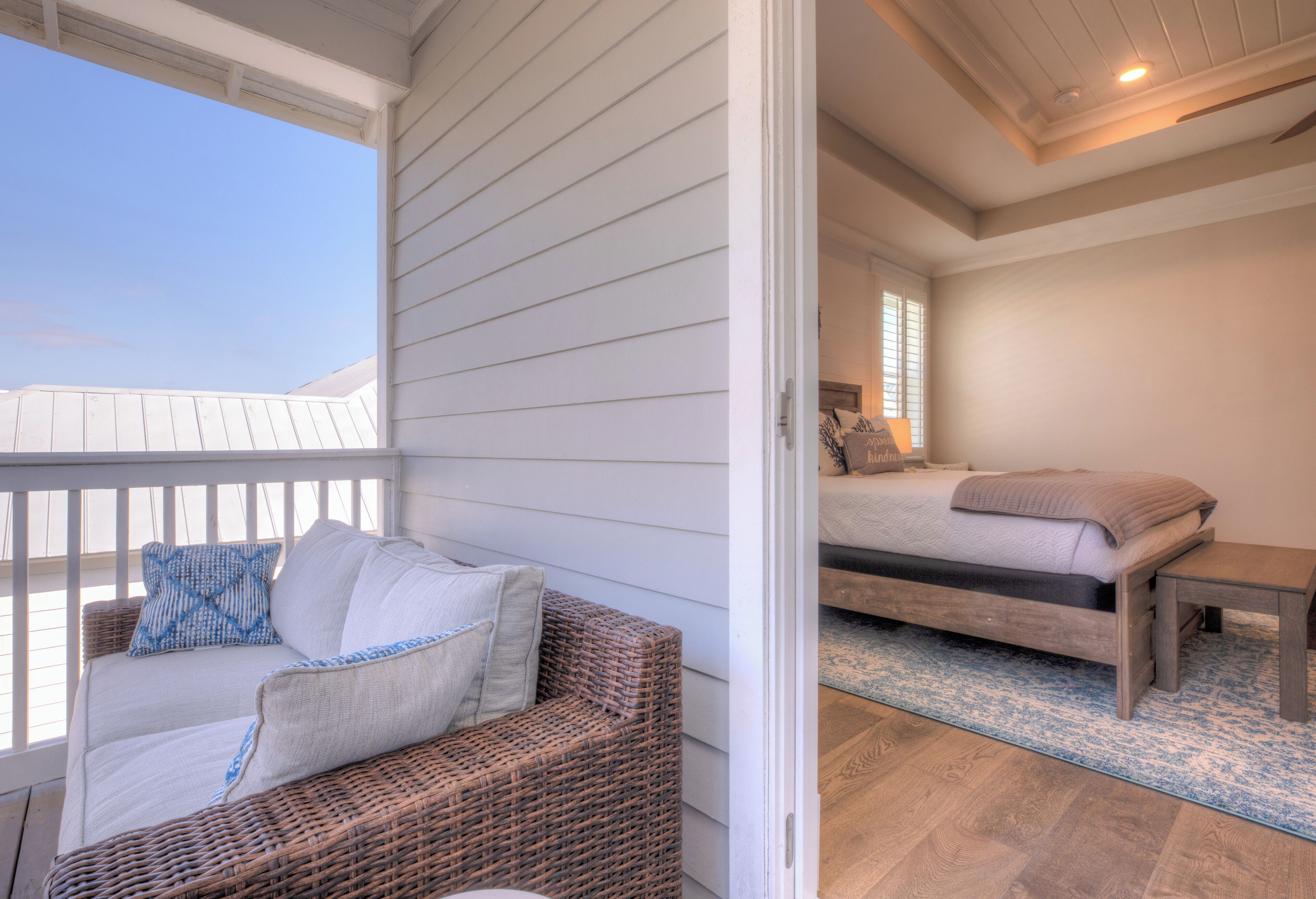 Un balcone con un divano in vimini e un letto con testiera in legno.