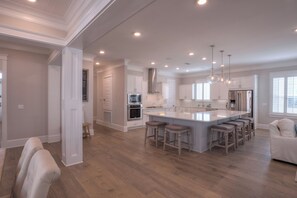 A spacious kitchen with a large island, bar stools, and modern appliances. - Coconut Cove by AvantStay | Deck w/ Hot Tub, Access to 2 Pools (Santa Rosa Beach)