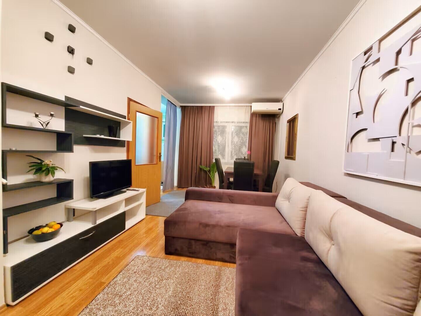 Un salon moderne avec un téléviseur à écran plat, un canapé, une table basse et une plante.