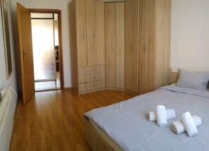 A bedroom with a bed, a wardrobe, and a door leading to another room.