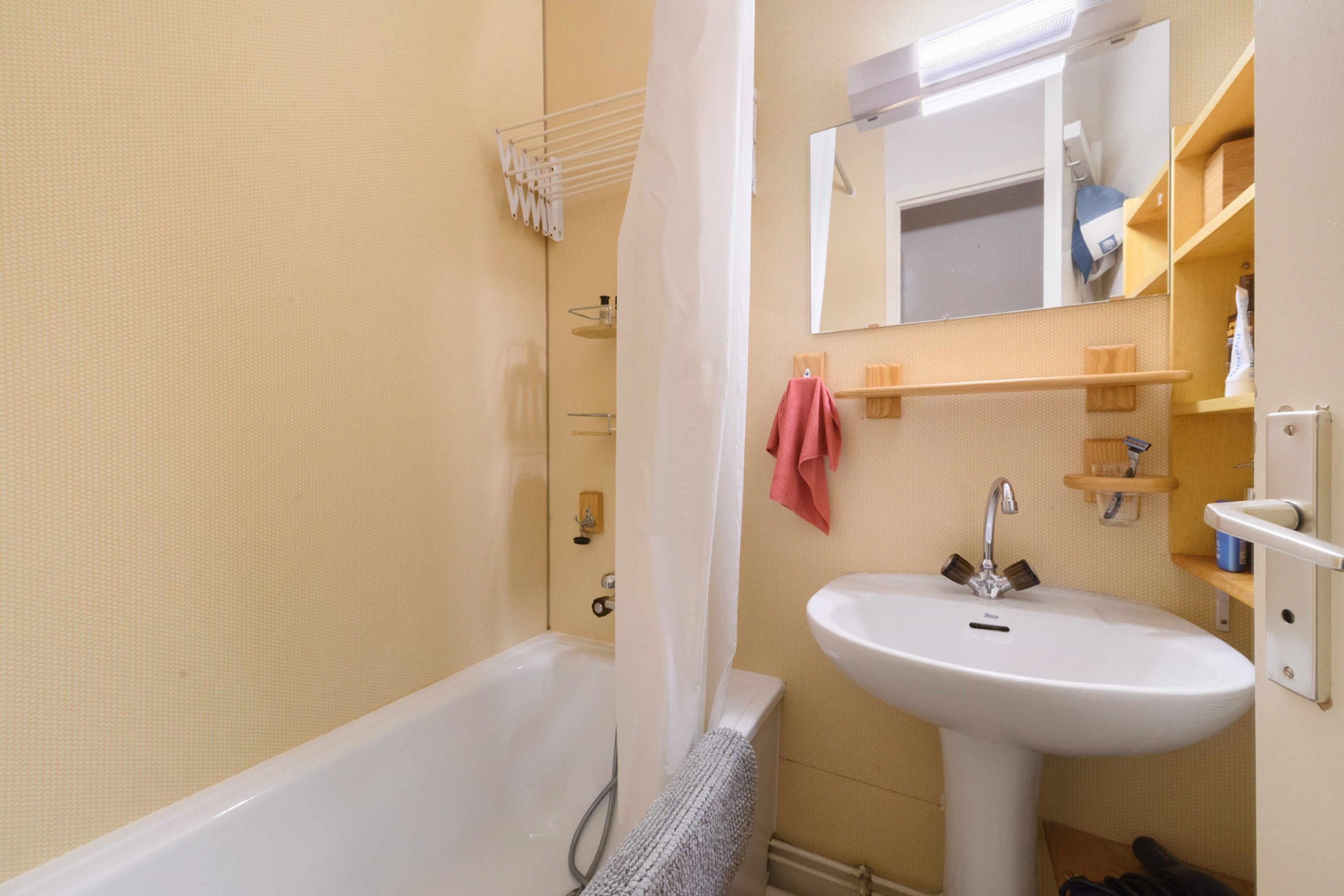 A bathroom with a bathtub, a sink, and a mirror.
