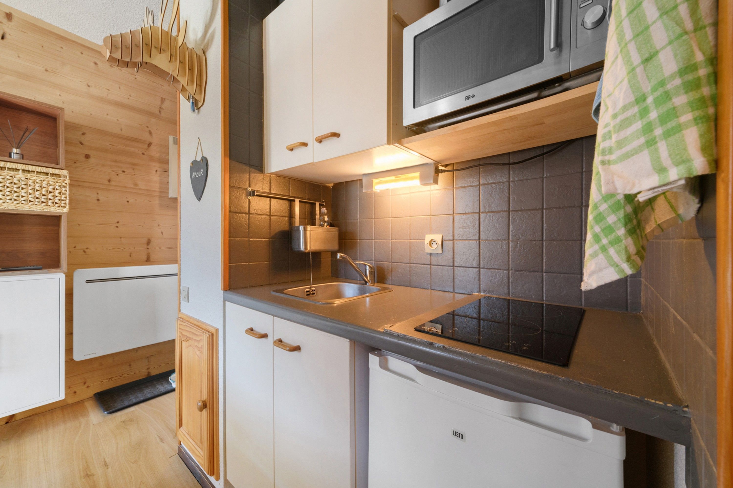 A compact kitchen with a microwave, sink, and cabinets.