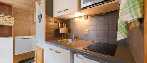 A compact kitchen with a microwave, sink, and cabinets.