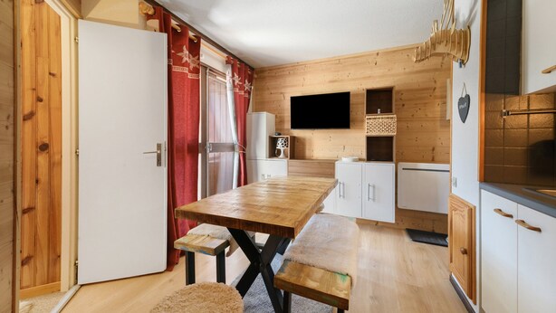 Een compacte keuken met houten kastjes, een inbouwoven en een flatscreen televisie.