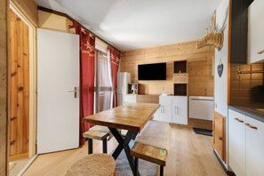 Una cocina compacta con armarios de madera, horno empotrado y televisor de pantalla plana.