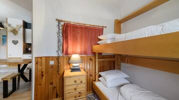 Ein Etagenbett mit Holz Kopfteil, ein Nachttisch mit Lampe und eine kleine Kommode mit Schubladen.
