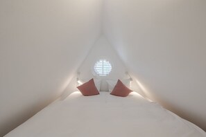 A tent-like room with a bed centered under a circular window, white walls, and two bedside lamps. - Beach Love Sylt, Germany (Sylt)