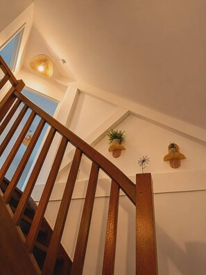 A wooden staircase with a view of the sky through a window, a wall-mounted light fixture, and two wall-mounted planters with plants. - Nature Lodge **** Monts du Cantal - Le Violon Cantal Emotion (Valette)