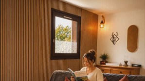 Ein gemütliches Wohnzimmer mit einer Couch, einem Couchtisch und einem Fenster mit Blick auf Grünflächen.