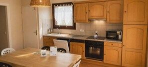 A compact kitchen with wooden cabinets, a sink, a microwave, and a dishwasher. - Nature Lodge **** Monts du Cantal - Le Violon Cantal Emotion (Valette)