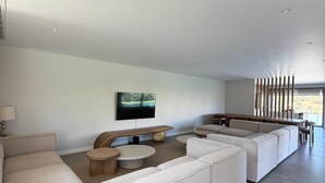 Ein modernes Wohnzimmer mit einer Eckcouch, einem Couchtisch und einem an der Wand montierten Fernseher.
