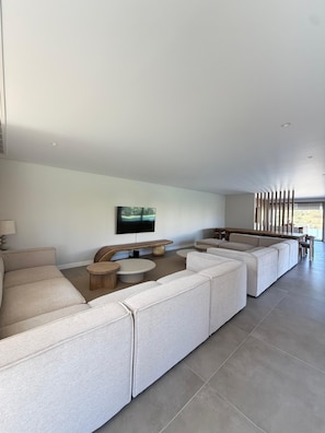Ein modernes Wohnzimmer mit einer Eckcouch, einem Couchtisch und einem an der Wand montierten Fernseher.