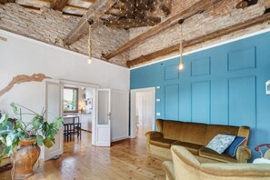 Ein Zimmer mit Holzboden, einem braunen Sofa, einer blauen Wand und einer Ziegeldecke.
