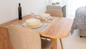 A dining area with a wooden table, beige chairs, and a bottle of olive oil. - Studio 4 Kalamata - Bright Escape in the Centre (Kalamata)