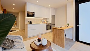 Una cocina moderna con armarios blancos, encimera de madera y un refrigerador.