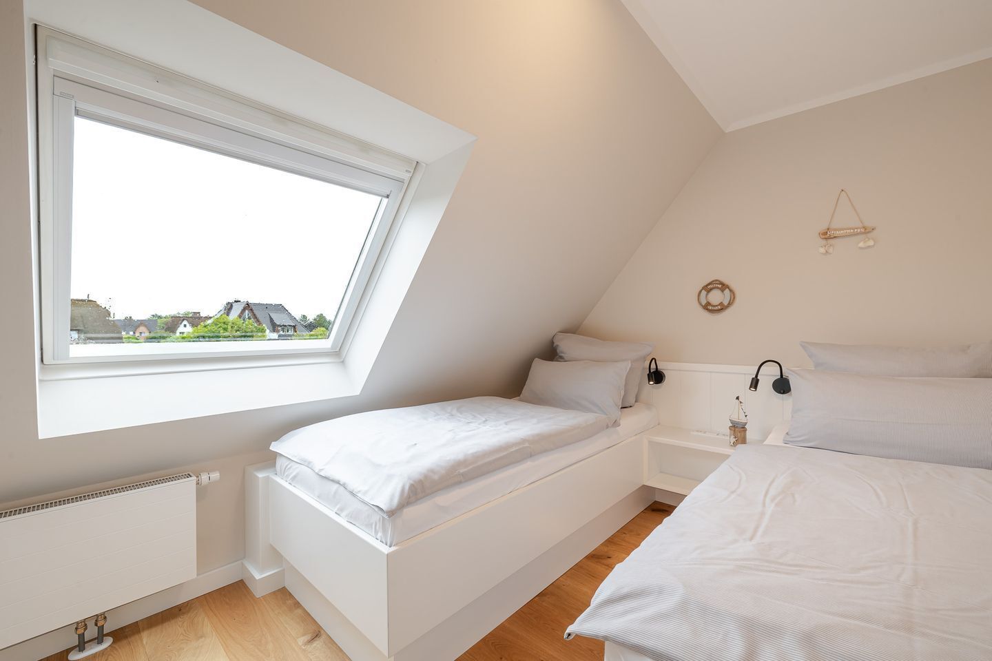 A bedroom with a sloped ceiling, a skylight, a radiator, and a bedside table with a lamp.